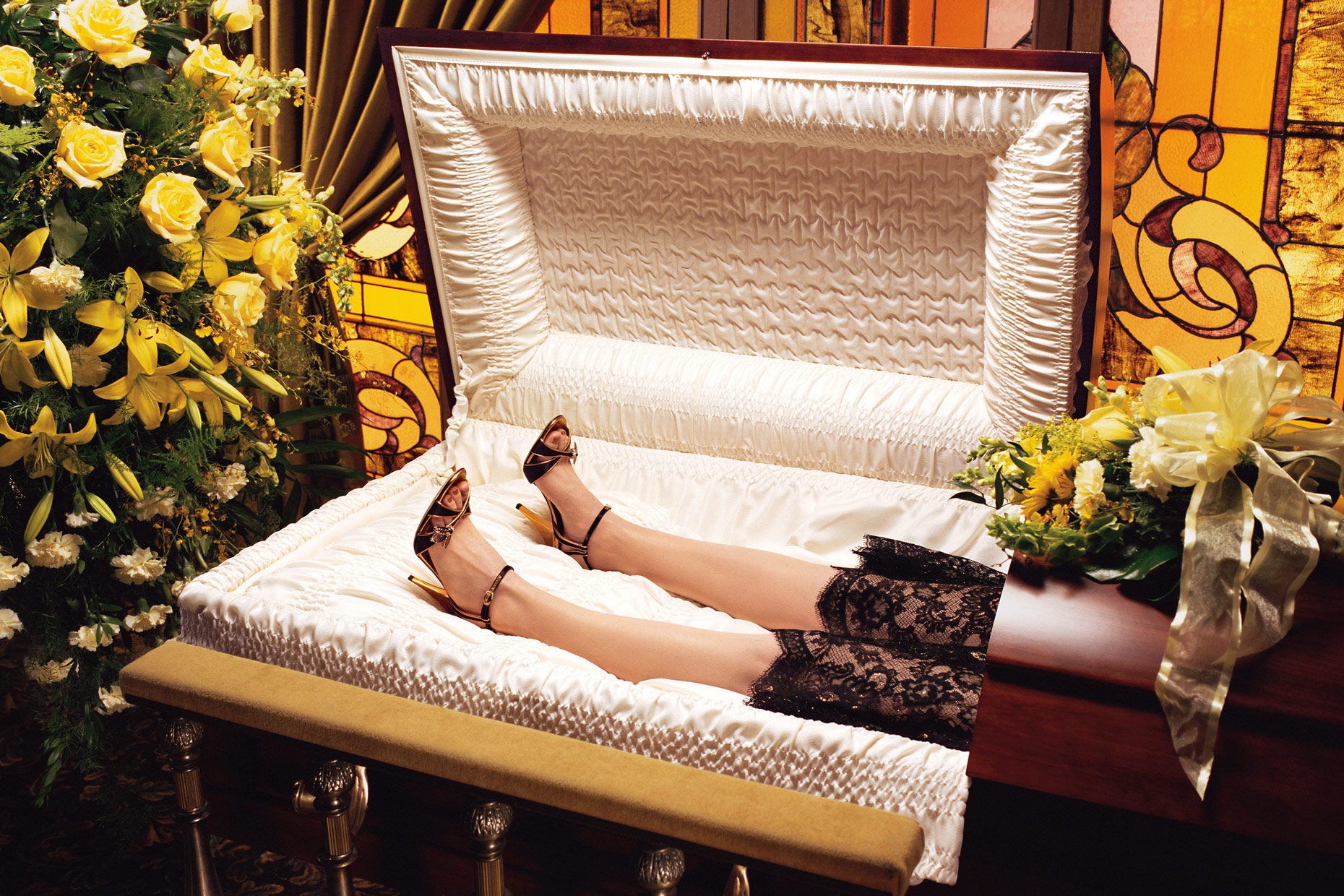 woman laying backward in a casket with high heel shoes | Conceptual photography by Saverio Truglia