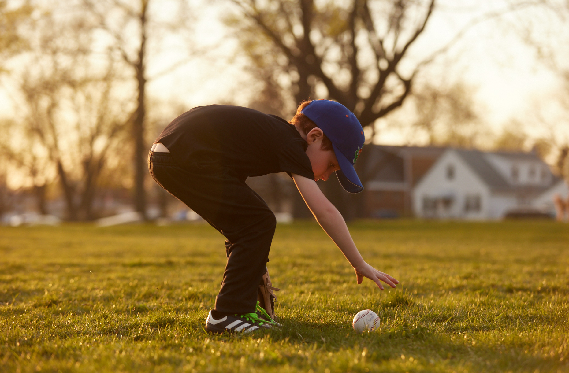 Boy picking up a baseball at sunset | Childrens photography by Saverio Truglia