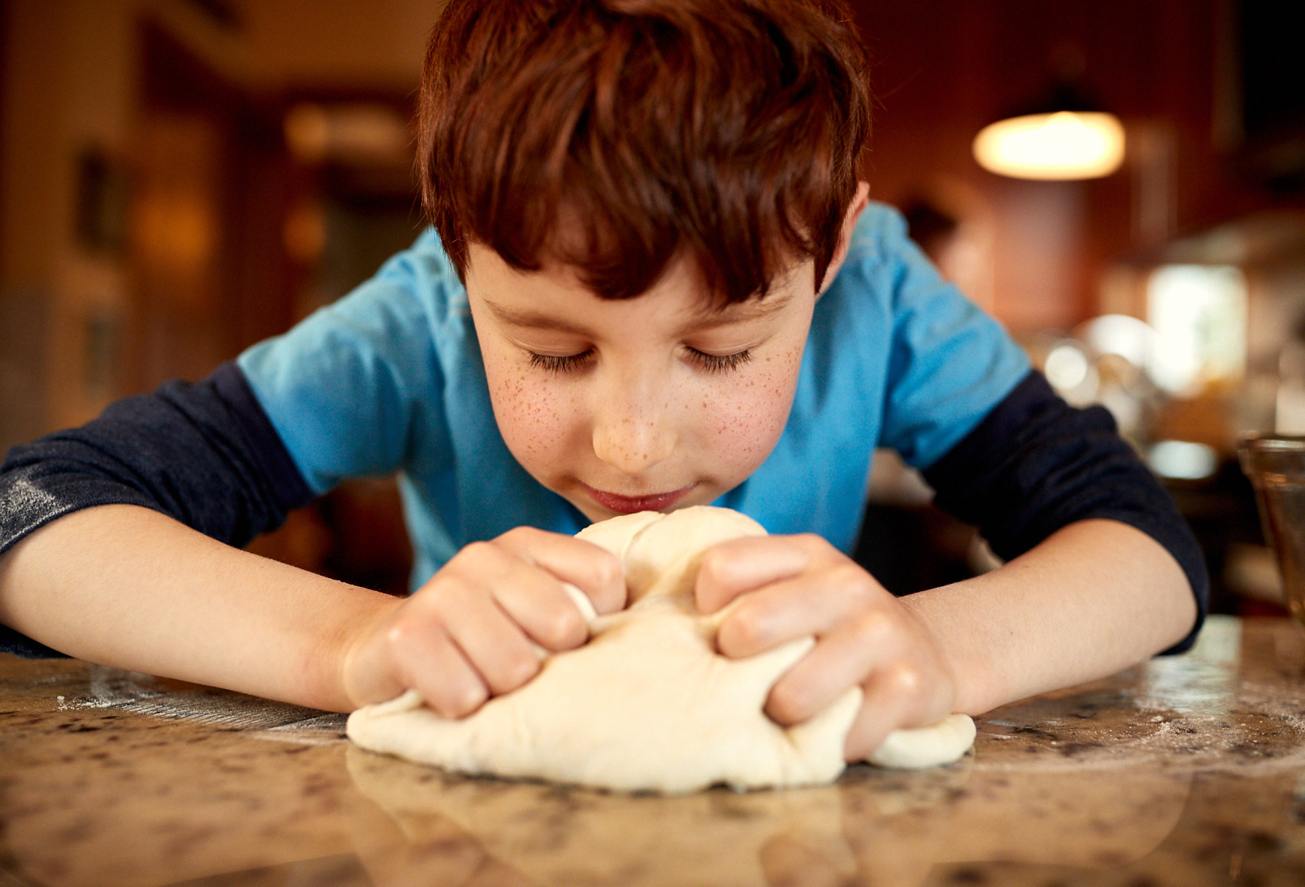 Boy kneading bread in kitchen | Childrens photography by Saverio Truglia