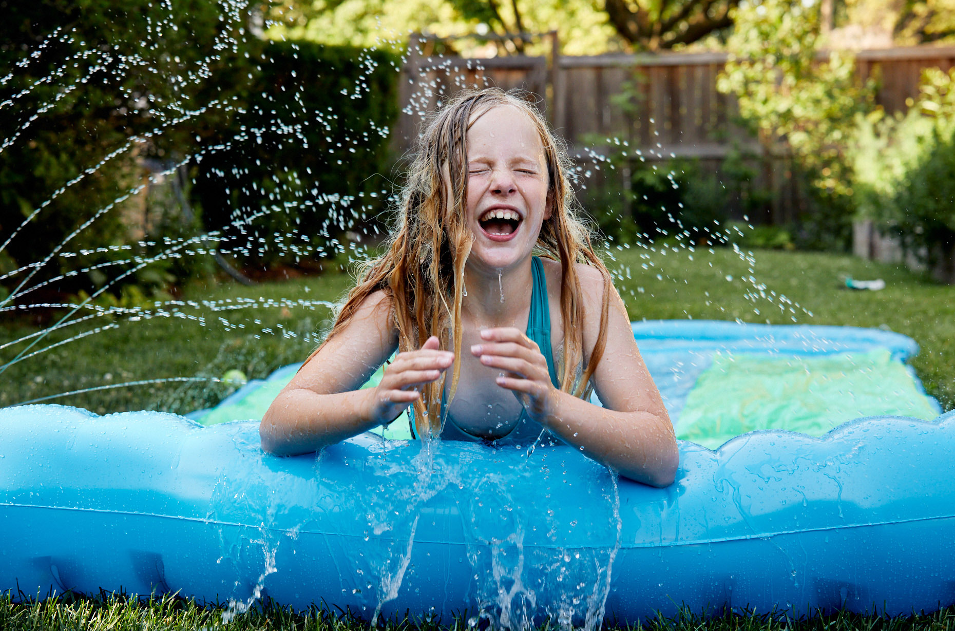 Tween girl on slip and slide in suburbs | Childrens photography by Saverio Truglia