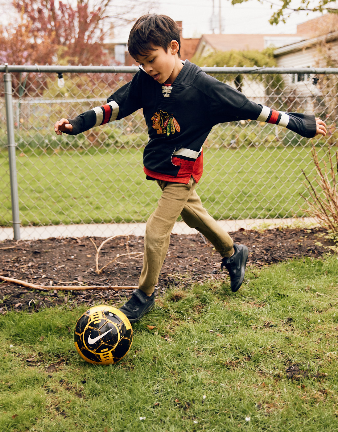 Boy kicking a Nike soccer ball in yard | Childrens photography by Saverio Truglia