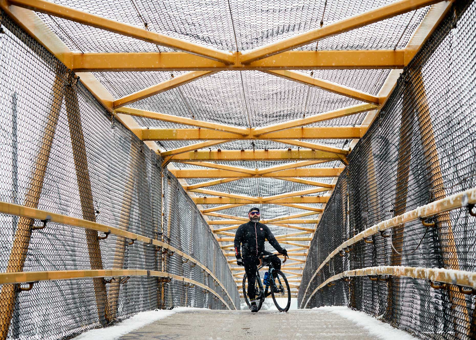Cyclist on a snowy cage bridge | lifestyle photography by Saverio Truglia