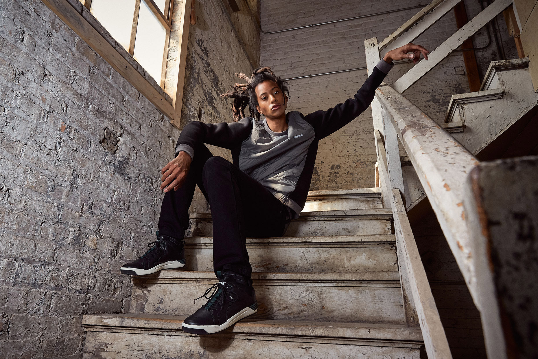 Young man with dreads on warehouse stairs | lifestyle photography by Saverio Truglia